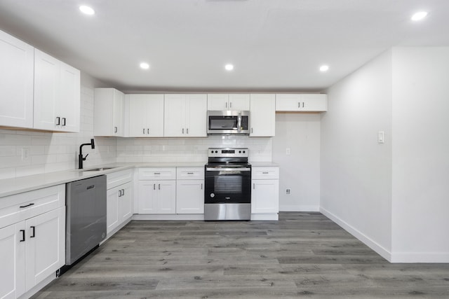 kitchen featuring white cabinets, appliances with stainless steel finishes, sink, and hardwood / wood-style floors