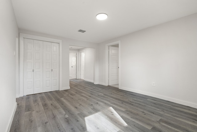 unfurnished bedroom with dark hardwood / wood-style flooring and a closet