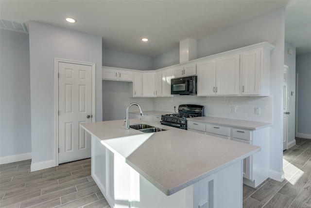 kitchen featuring sink, an island with sink, white cabinetry, and black appliances