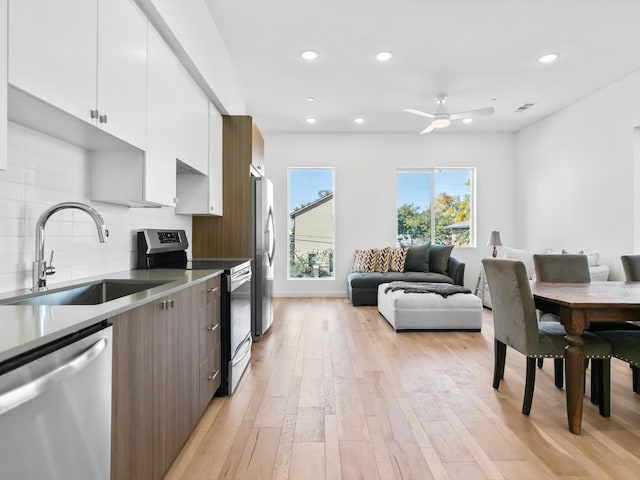 kitchen featuring sink, decorative backsplash, light wood-type flooring, white cabinetry, and stainless steel appliances