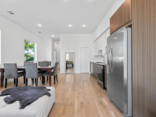 kitchen featuring sink, white cabinets, light wood-type flooring, and appliances with stainless steel finishes