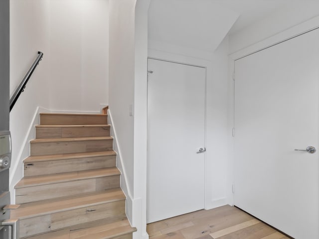 stairs with wood-type flooring and vaulted ceiling