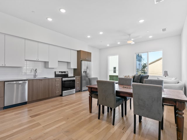 dining space with ceiling fan, light hardwood / wood-style floors, and sink