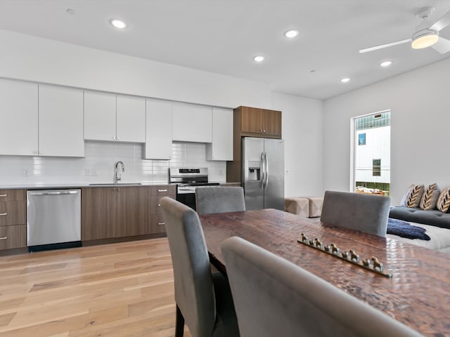 dining room with ceiling fan, sink, and light hardwood / wood-style flooring