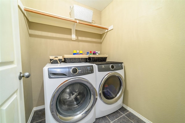 laundry area with washer and dryer and dark tile patterned flooring