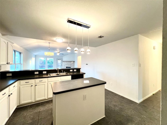 kitchen with sink, a kitchen island, pendant lighting, ceiling fan, and white cabinets