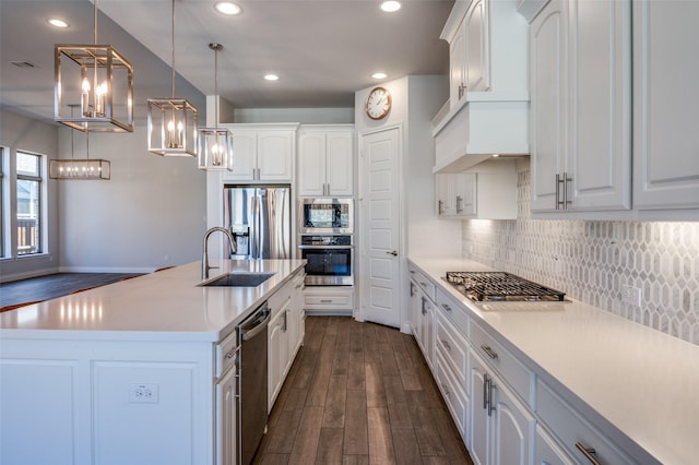 kitchen featuring appliances with stainless steel finishes, dark hardwood / wood-style flooring, sink, white cabinetry, and hanging light fixtures