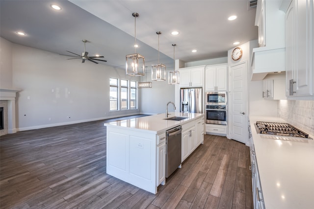 kitchen with appliances with stainless steel finishes, a kitchen island with sink, dark wood-type flooring, pendant lighting, and white cabinets