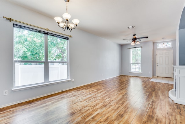 unfurnished living room with ceiling fan with notable chandelier and light wood-type flooring