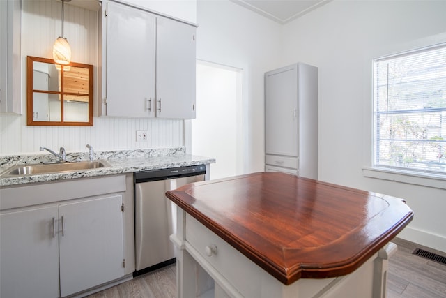 kitchen featuring sink, light stone counters, stainless steel dishwasher, white cabinets, and light wood-type flooring