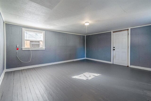 basement featuring a textured ceiling, cooling unit, and dark hardwood / wood-style floors