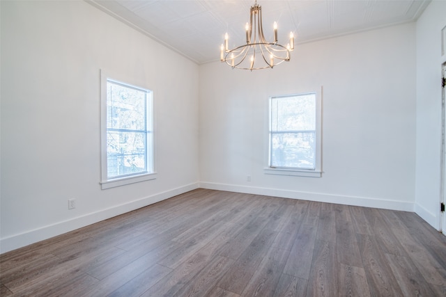 spare room featuring crown molding, hardwood / wood-style floors, and a notable chandelier