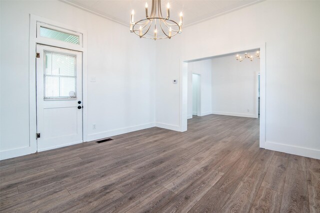 unfurnished dining area with dark hardwood / wood-style floors, an inviting chandelier, and ornamental molding