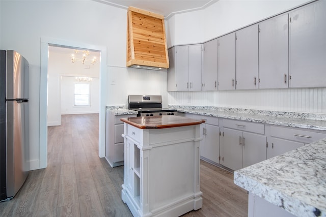 kitchen featuring stainless steel appliances, wood counters, a notable chandelier, light hardwood / wood-style floors, and a kitchen island