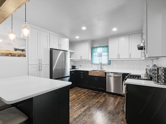 kitchen featuring stainless steel appliances, white cabinetry, sink, and decorative light fixtures