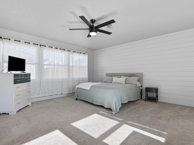 carpeted bedroom with wooden walls and ceiling fan