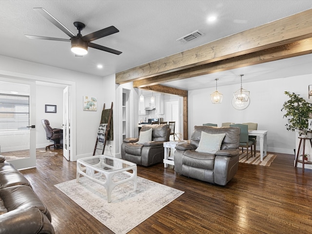 living room featuring dark hardwood / wood-style flooring, ceiling fan with notable chandelier, a textured ceiling, and beam ceiling