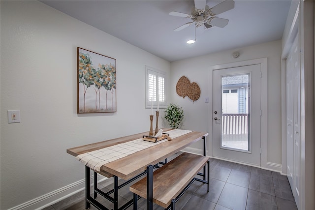 dining space featuring ceiling fan and dark tile patterned flooring