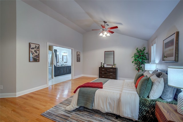 bedroom featuring ceiling fan, vaulted ceiling, connected bathroom, and light hardwood / wood-style flooring