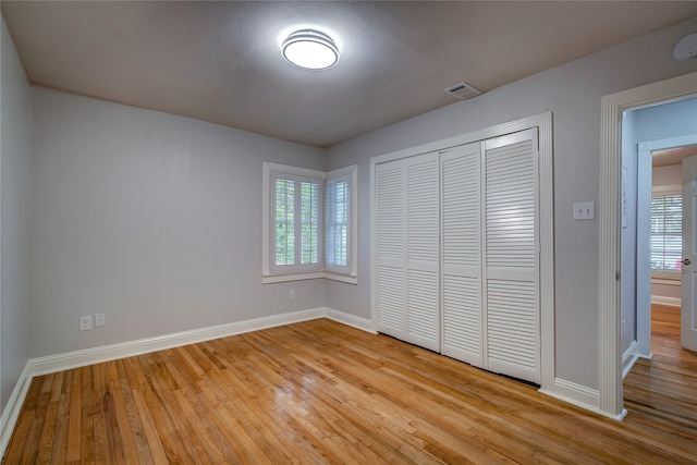 unfurnished bedroom with light wood-type flooring and a closet