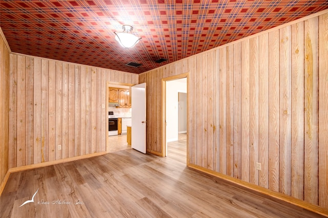 spare room with wooden walls and light wood-type flooring