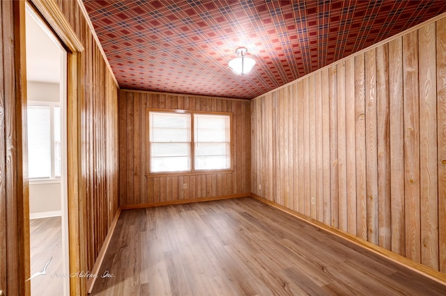 spare room with hardwood / wood-style floors and wooden walls