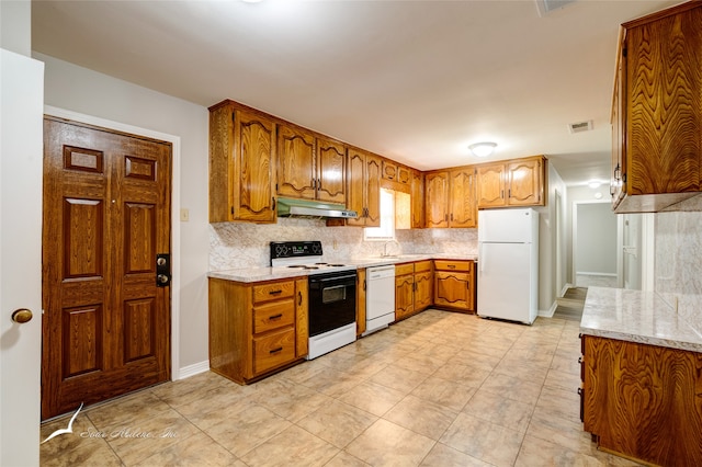 kitchen featuring decorative backsplash, sink, light stone countertops, and white appliances