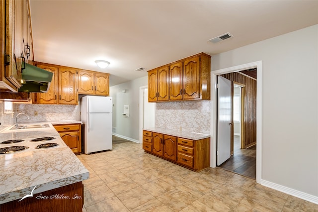 kitchen featuring backsplash, sink, and white refrigerator