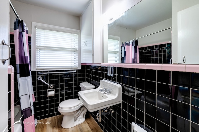 bathroom featuring a healthy amount of sunlight, wood-type flooring, and tile walls