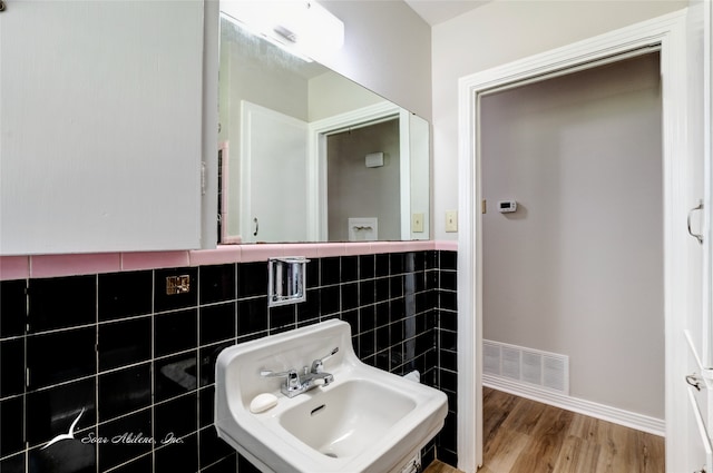 bathroom featuring wood-type flooring, tile walls, and sink