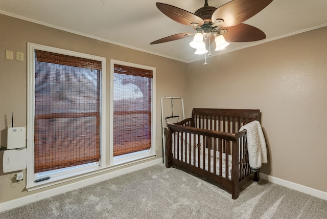 carpeted bedroom featuring ceiling fan, ornamental molding, and a nursery area