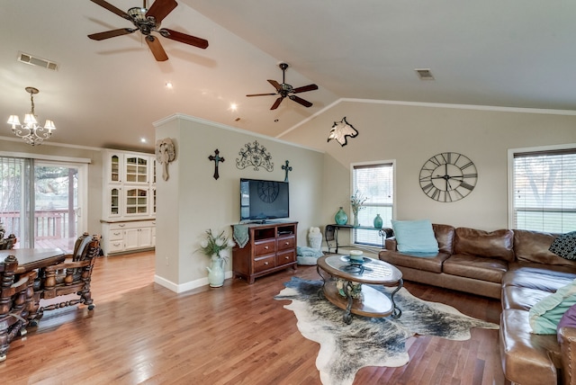 living room featuring light hardwood / wood-style flooring, plenty of natural light, lofted ceiling, and crown molding