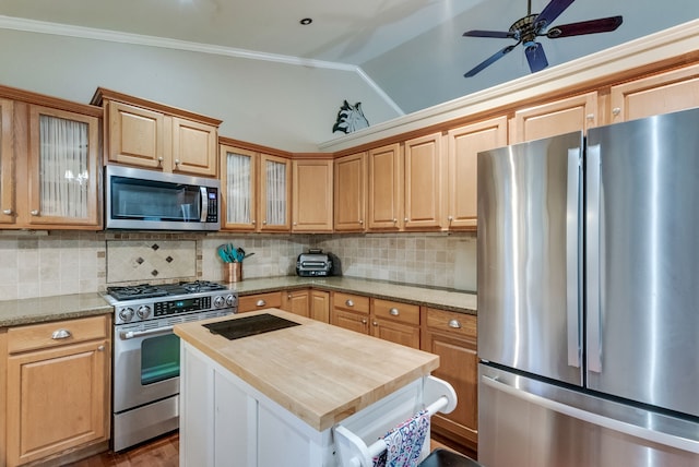 kitchen with a center island, backsplash, vaulted ceiling, appliances with stainless steel finishes, and butcher block counters