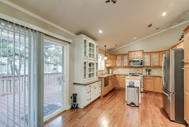 kitchen with a center island, hanging light fixtures, crown molding, lofted ceiling, and appliances with stainless steel finishes