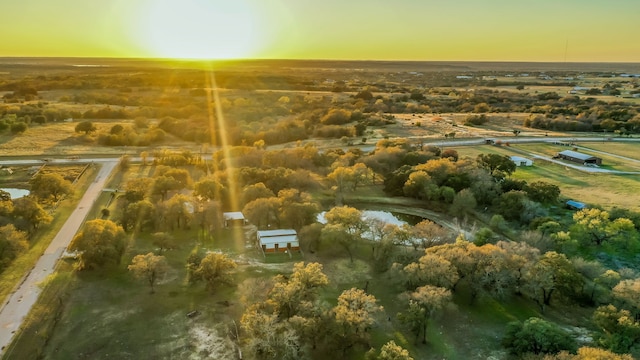 aerial view at dusk featuring a rural view and a water view