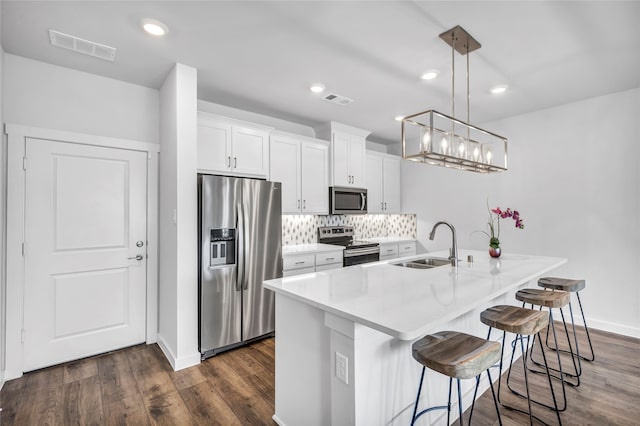 kitchen with sink, dark hardwood / wood-style flooring, decorative light fixtures, white cabinets, and appliances with stainless steel finishes