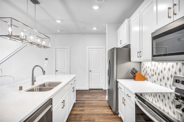 kitchen with dark hardwood / wood-style flooring, stainless steel appliances, sink, white cabinetry, and hanging light fixtures