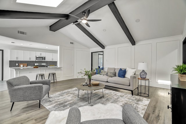 living room with vaulted ceiling with beams, light hardwood / wood-style floors, and ceiling fan