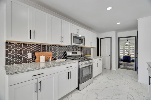 kitchen with appliances with stainless steel finishes, backsplash, white cabinetry, and light stone counters