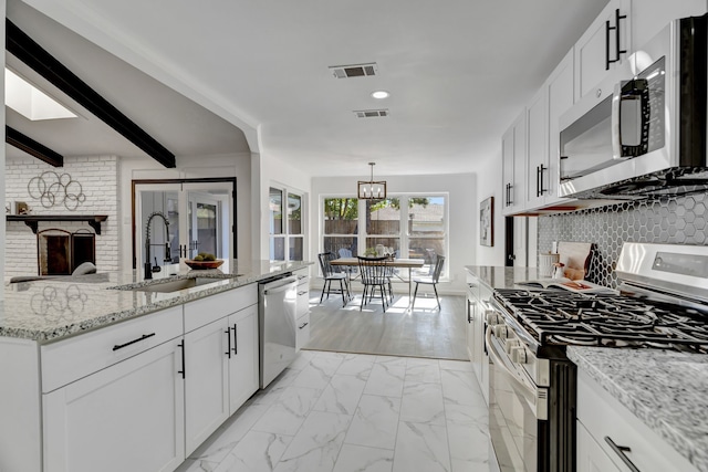 kitchen with beam ceiling, stainless steel appliances, white cabinetry, and sink