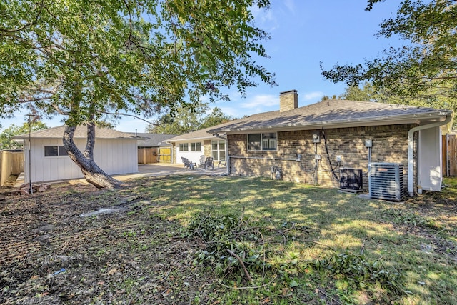 rear view of house with central AC unit, a patio area, and a yard