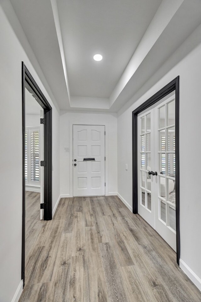 hallway featuring a raised ceiling, french doors, and light hardwood / wood-style flooring