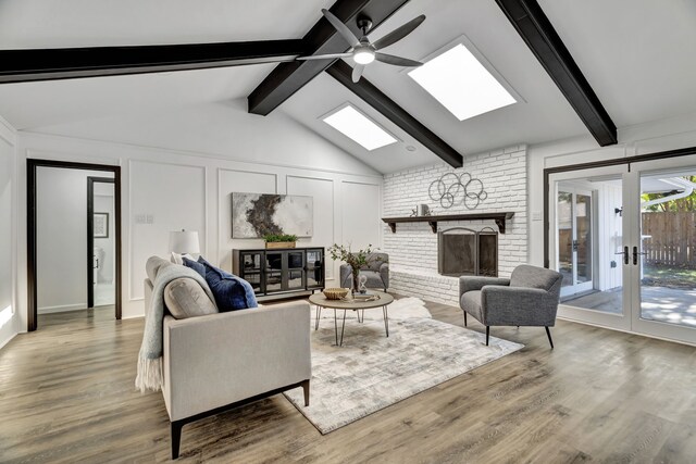 living room with a fireplace, lofted ceiling with skylight, hardwood / wood-style floors, and ceiling fan