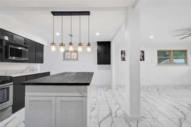 kitchen with ceiling fan, a center island, decorative light fixtures, and appliances with stainless steel finishes