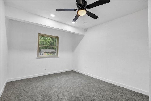 empty room with dark colored carpet and ceiling fan