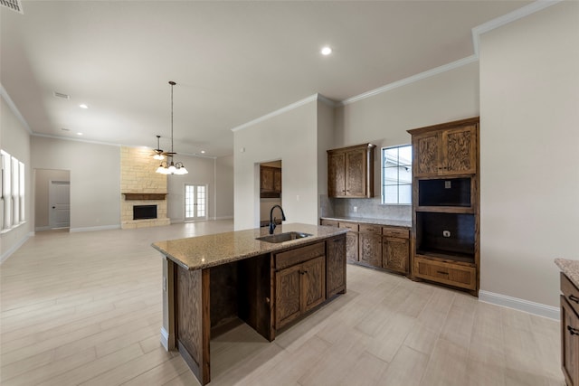 kitchen featuring an island with sink, light stone countertops, sink, and a wealth of natural light