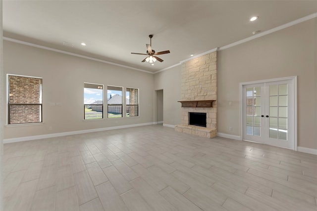 unfurnished living room featuring crown molding, ceiling fan, a stone fireplace, french doors, and light wood-type flooring