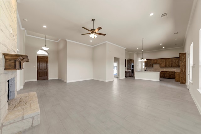 unfurnished living room featuring a stone fireplace, sink, ceiling fan, ornamental molding, and light hardwood / wood-style floors