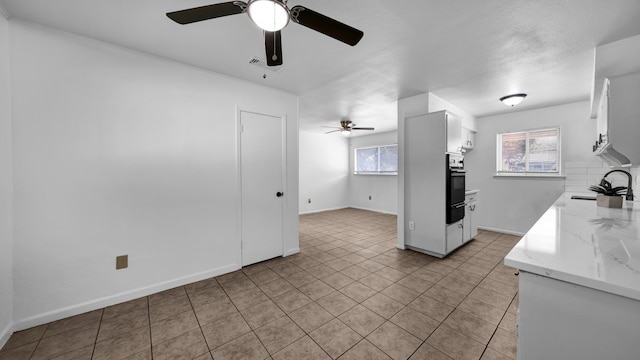 kitchen with white cabinets, sink, tasteful backsplash, black oven, and light stone counters