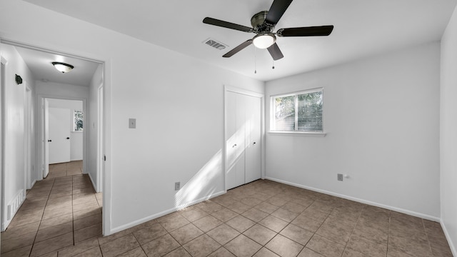 unfurnished bedroom with light tile patterned floors, a closet, and ceiling fan